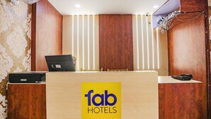 Un comptoir d’accueil avec un ordinateur portable, un téléphone et un panneau indiquant « Fab Hotels ».