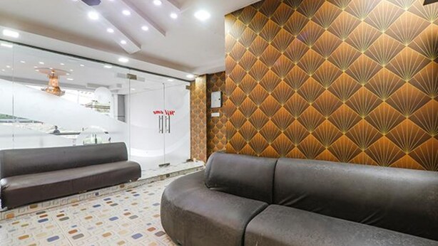 A modern lobby with a leather sofa, patterned wall, and a glass partition. - FabHotel A One Inn (Lucknow)