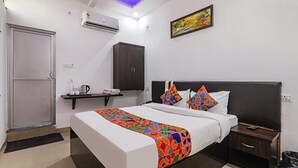 A modern hotel room with a large bed, a bedside table, a nightstand, a wardrobe, and an air conditioning unit. - FabHotel A One Inn (Lucknow)