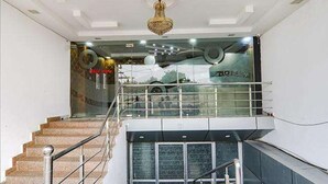 A staircase with a glass railing leading to a second floor, a chandelier, and a sign with partially visible text. - FabHotel A One Inn (Lucknow)