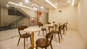 Un espace de restauration moderne avec des murs en verre, un escalier, ainsi que plusieurs tables et chaises.
