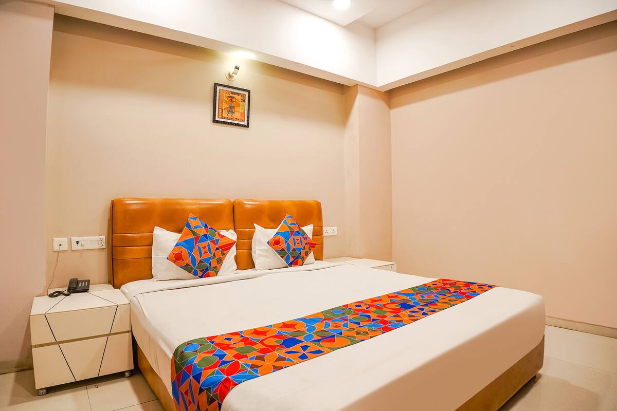 A neatly arranged hotel room with a bed, a nightstand, and a wall-mounted light fixture.