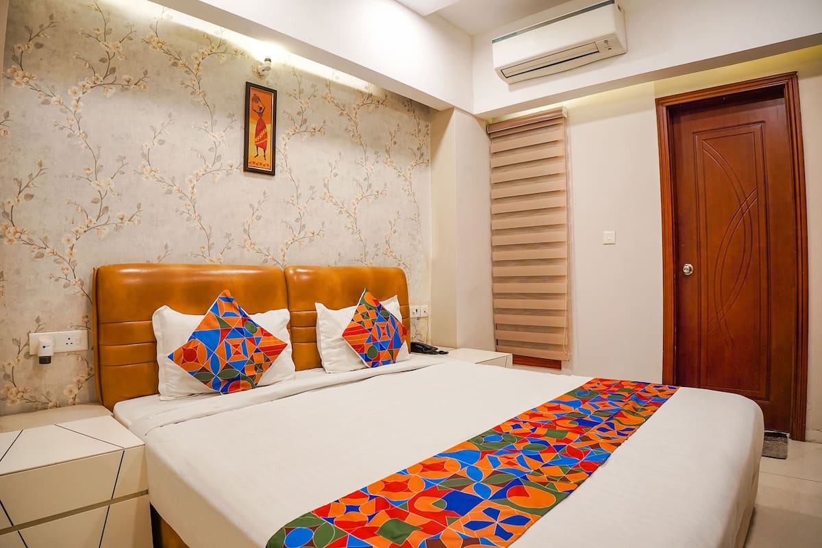A neatly arranged bedroom with a bed, a nightstand, a wall-mounted air conditioner, and a door.
