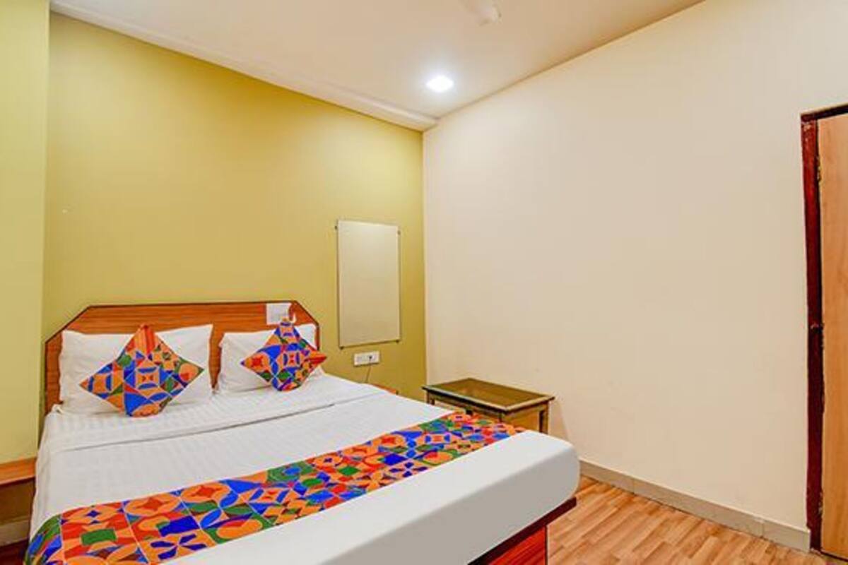 A bedroom with a bed, a nightstand, a mirror, and a door.