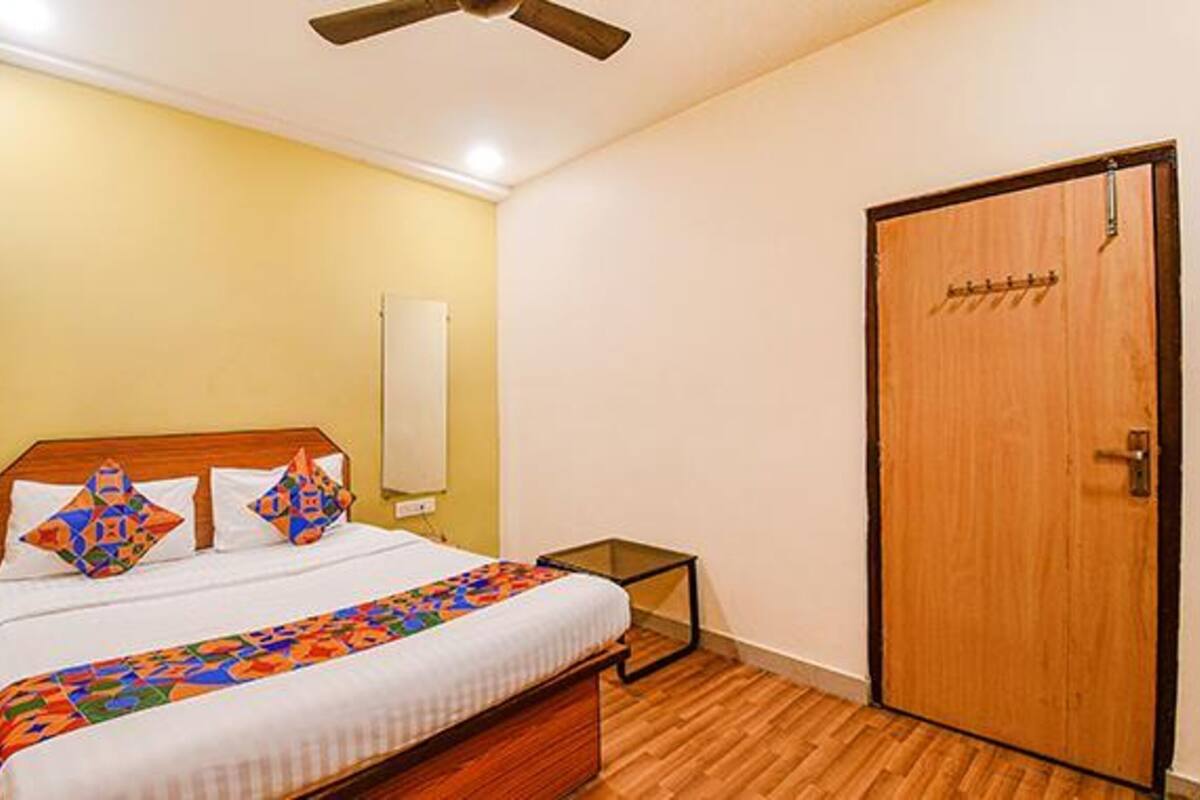 A bedroom with a bed, a wooden door, and a ceiling fan.