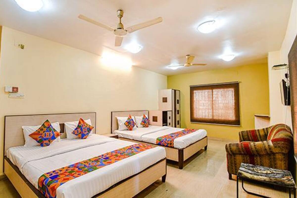A hotel room with two beds, a ceiling fan, and a window.