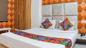 A bedroom with a bed, a bedside table, and a headboard. - Fabhotel The Pannis (Bhopal)