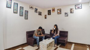 A room with two sofas, a coffee table, and a wall decorated with framed pictures. - Fabhotel The Pannis (Bhopal)