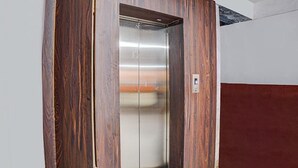An elevator with a wooden exterior and a metallic interior. - Fabhotel The Pannis (Bhopal)