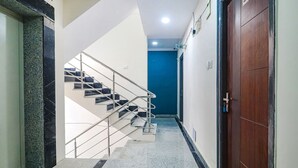 A hallway with a staircase, a blue door, and a wooden door. - FabHotel Broholic Suites I (Hyderabad)