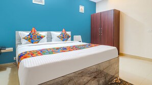 A bedroom with a bed, a wardrobe, and two framed pictures on the wall. - FabHotel Broholic Suites I (Hyderabad)