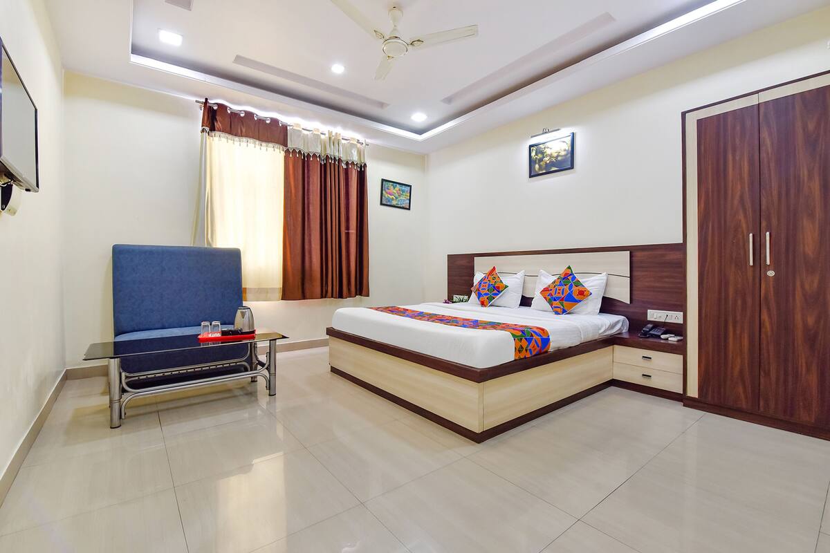 A modern bedroom with a bed, bedside table, wardrobe, and a desk with a chair.