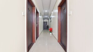 Un pasillo largo y estrecho con puertas de madera a ambos lados, que conduce a una habitación al final.