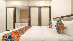 A hotel room with a bed, a colorful bedspread, a window, and a wardrobe. - FabHotel SR Hitech City (Hyderabad)