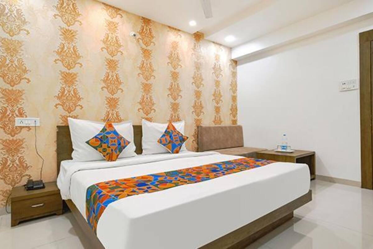 A hotel room with a large bed, two pillows, a nightstand, and a water bottle.