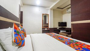A hotel room with a bed, a television, and a mirror. - Fabhotel Shravan (Nagpur)