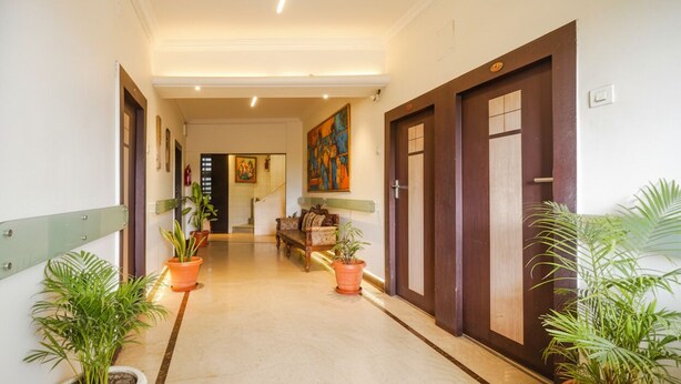 A hallway with potted plants, a bench, and doors leading to rooms. - Fabhotel Shravan (Nagpur)