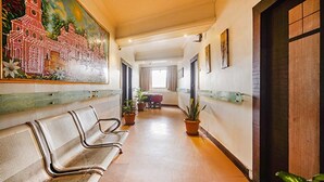 A hotel corridor with a bench, potted plants, and a mural on the wall. - Fabhotel Shravan (Nagpur)