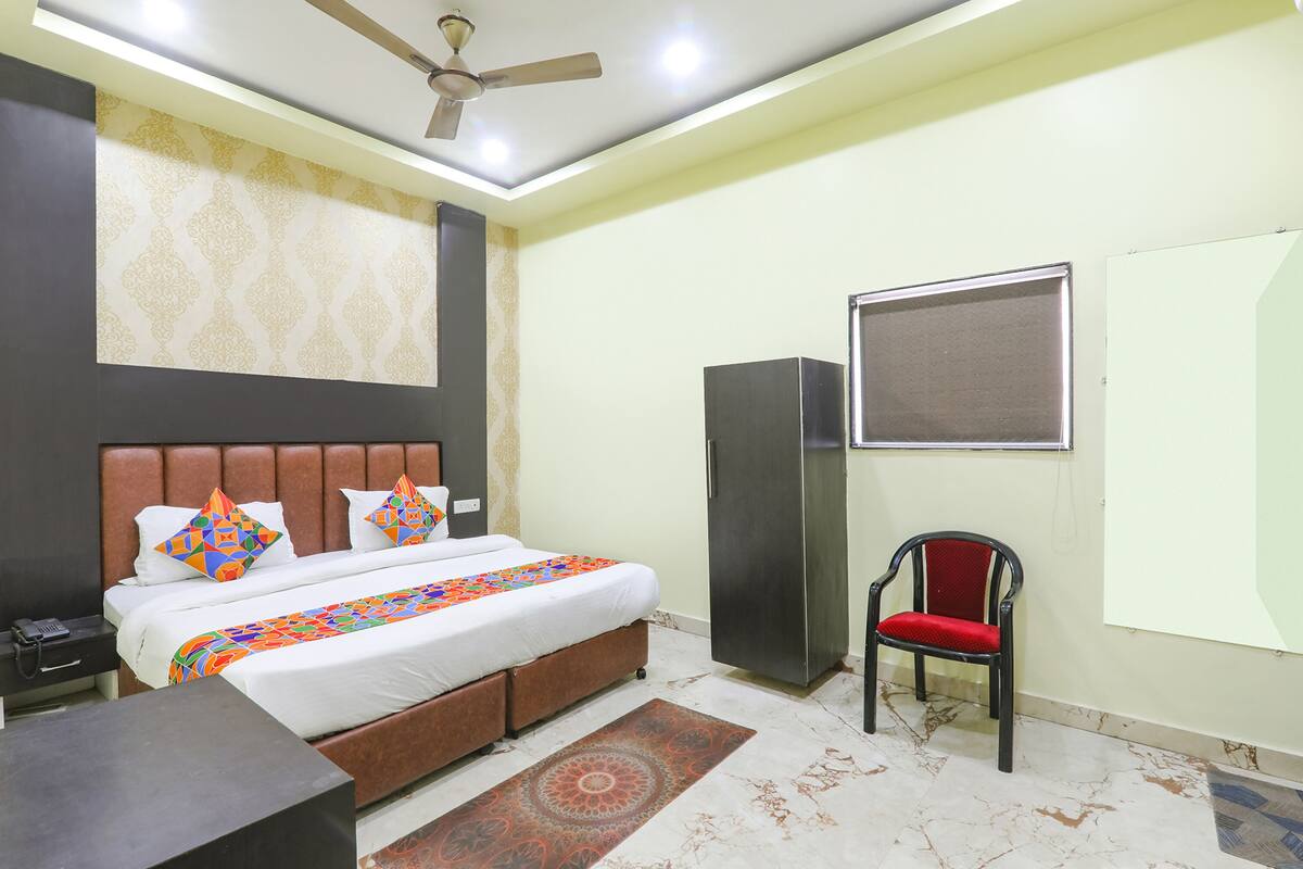 A bedroom with a bed, a desk, a chair, a wardrobe, and a ceiling fan.
