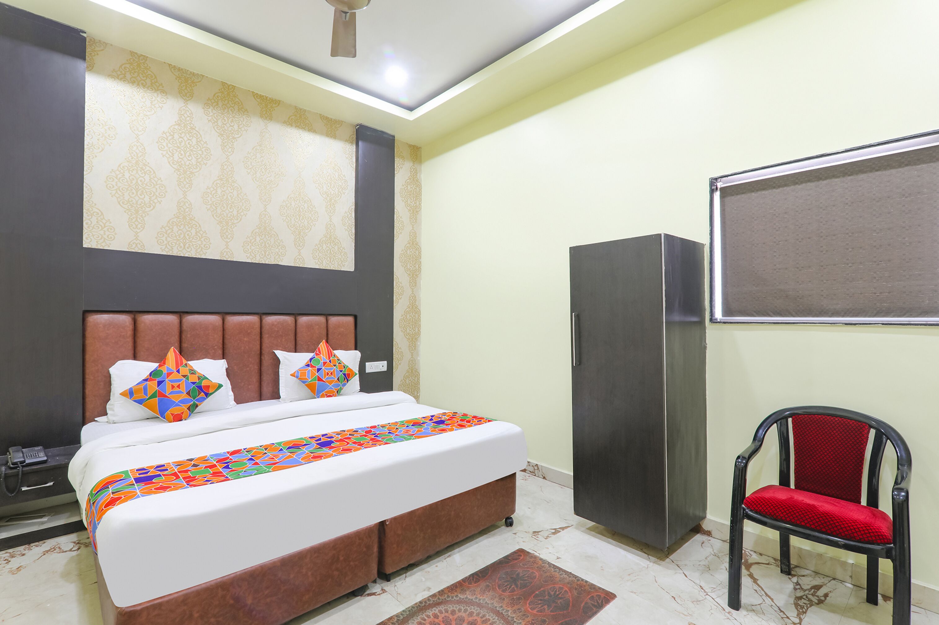 A hotel room with a bed, a wardrobe, and a chair.
