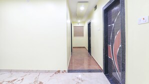 Un pasillo con suelo de mármol, paredes de color amarillo claro y una puerta con un panel de vidrio decorativo.