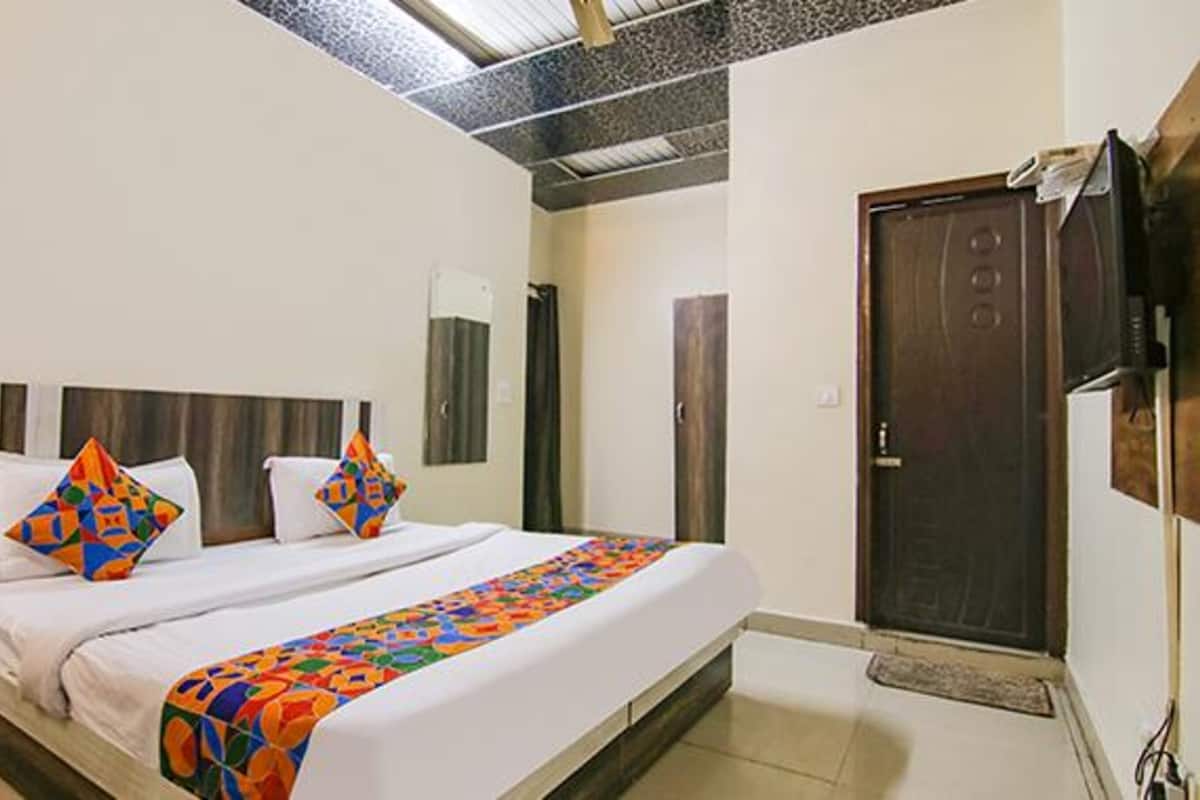 A hotel room with a bed, a TV mounted on the wall, and a door.