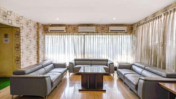 Una sala de estar moderna con un sofá modular, una mesa de centro y un ventanal con cortinas.