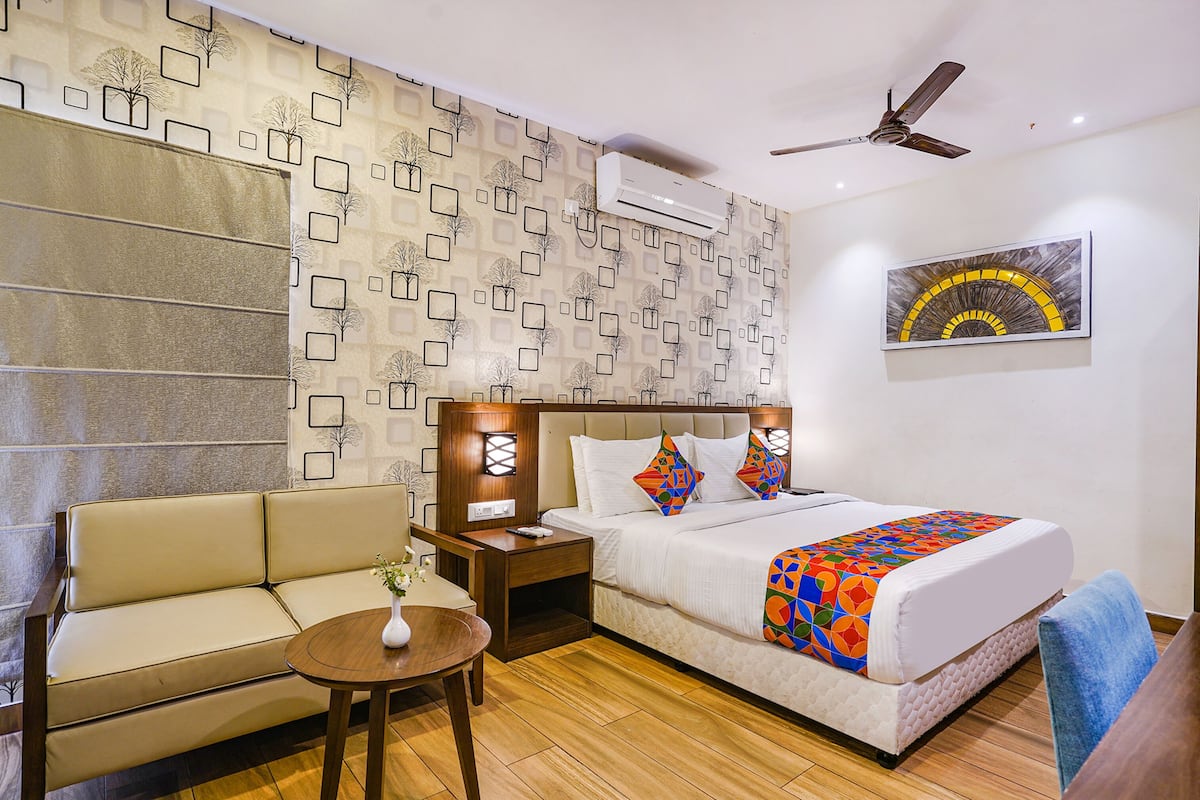 Una habitación de hotel con cama, sofá, una mesita y un ventilador de techo.