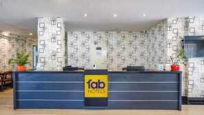 Un mostrador de recepción de hotel con un cartel de 'fab hotels', un reloj y papel tapiz estampado.