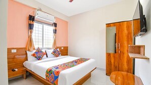 A bedroom with a wooden bed, a TV mounted on the wall, and a wardrobe. - FabHotel Silver 9 (Paud)