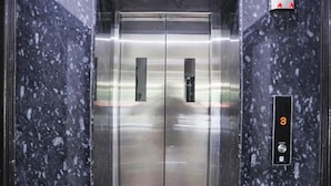 An elevator with a digital display showing the number 3, metallic interior, and marble walls.
