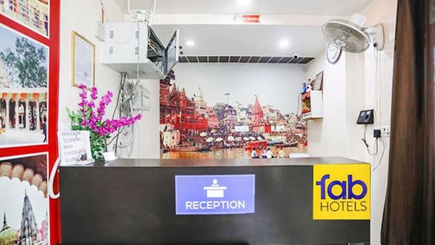 A hotel reception desk with a 'Reception' sign, a 'fab hotels' logo, and a cityscape mural in the background.