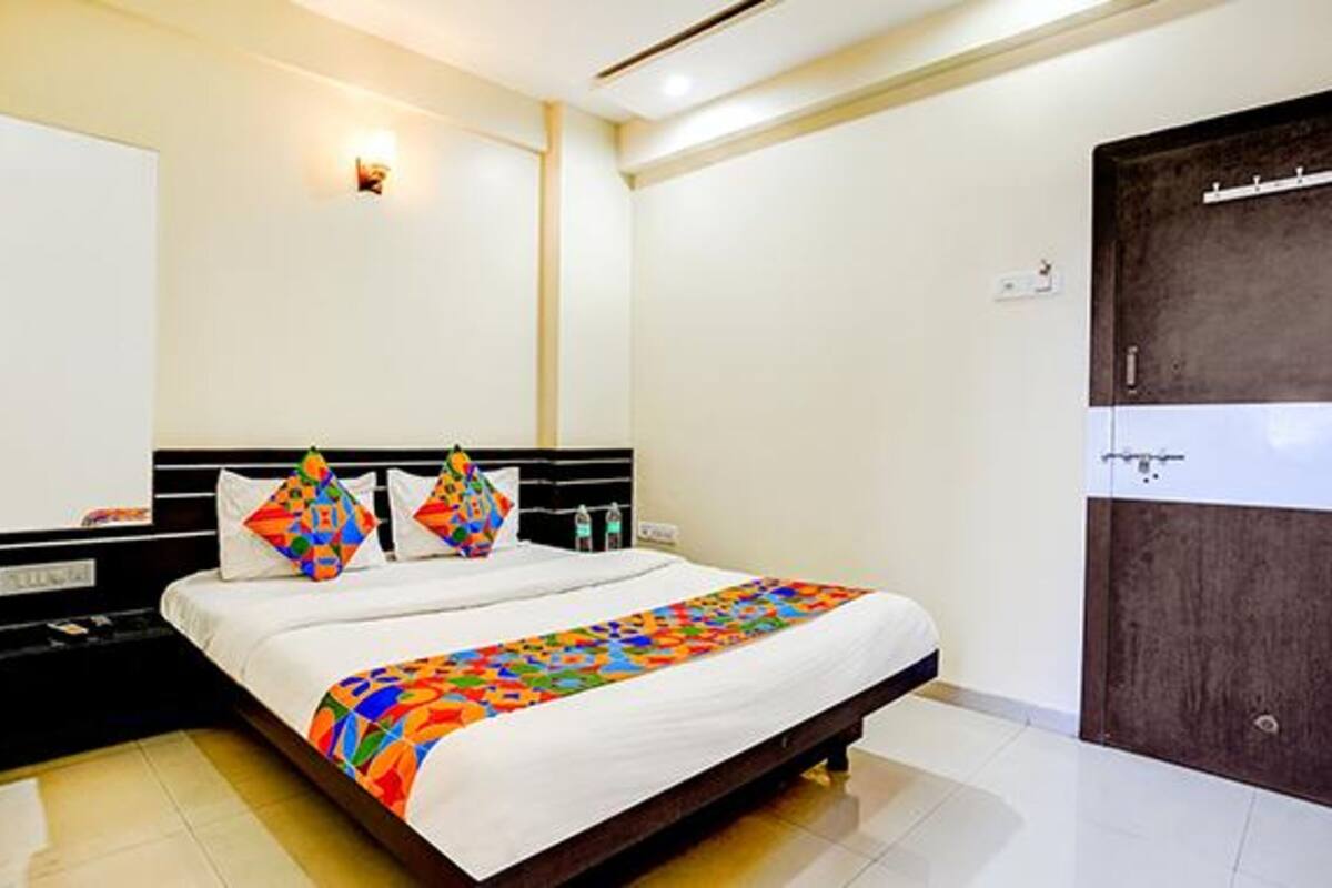 Quarto de hotel com cama, guarda-roupa e luminária na parede.