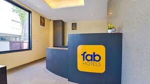 A reception desk with a 'fab hotels' sign, a window with a view, and a small plant on top. - Fabhotel Prime Pink City Park (Jaipur)