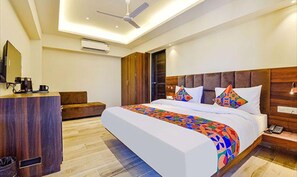 Ein Hotelzimmer mit Bett, Schreibtisch mit Kaffeemaschine, Kleiderschrank und Deckenventilator.