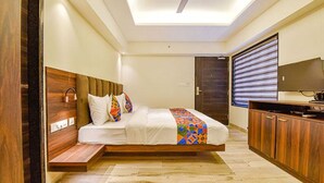 A modern hotel room with a bed, wooden headboard, built-in bench, and a TV on a wooden cabinet. - Fabhotel Prime Pink City Park (Jaipur)