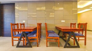 A dining area with wooden tables and chairs, a tiled wall, and a door. - Fabhotel Prime Pink City Park (Jaipur)