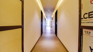 A long, narrow hallway with a light-colored floor and walls, leading to a bright room at the end. - Fabhotel Prime Pink City Park (Jaipur)