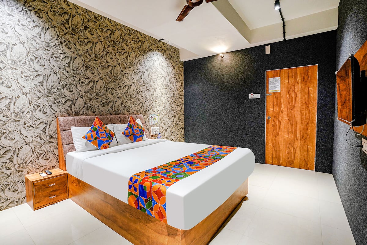 A modern bedroom with a large bed, wooden headboard, and a patterned wallpaper.