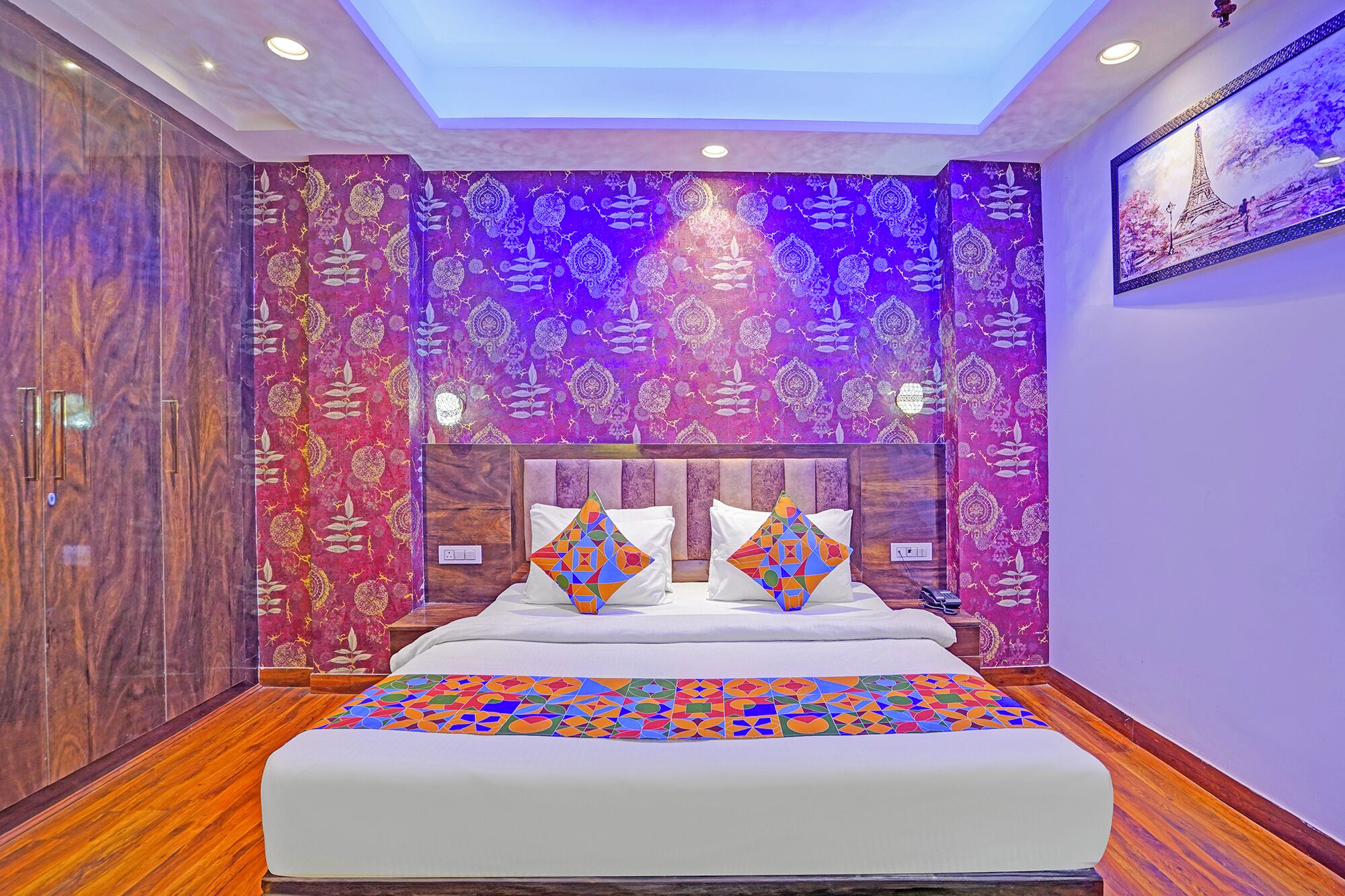 A bedroom with a bed, patterned wallpaper, and a ceiling light.