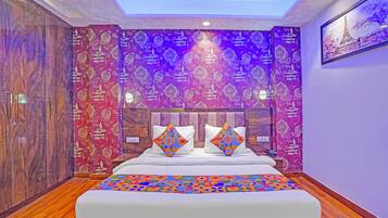 A bedroom with a bed, patterned wallpaper, and a ceiling light.