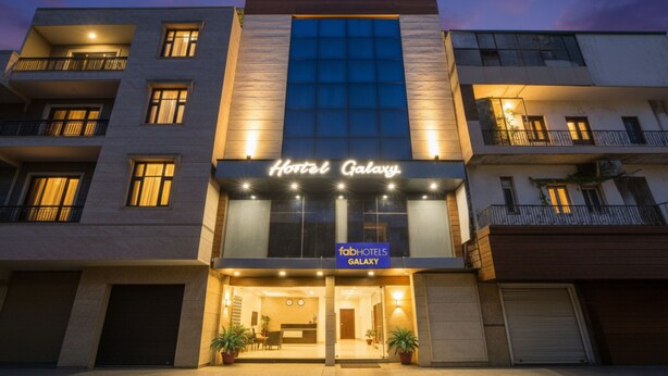 Un hôtel à plusieurs étages, reconnaissable à son grand panneau indiquant « Hôtel Galaxy ».