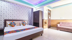 Una habitación de hotel moderna con una cama grande, un armario, un sofá rosa y una pared con estampado.