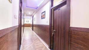 Un pasillo de hotel con paneles de madera, piso estampado y una puerta con un número.