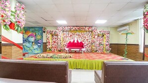 Una sala con escenario, decoraciones florales y alfombra verde.