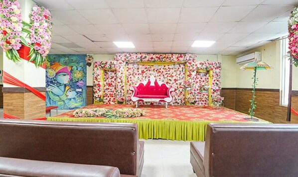 Une salle avec une scène, des décorations florales et une moquette verte.