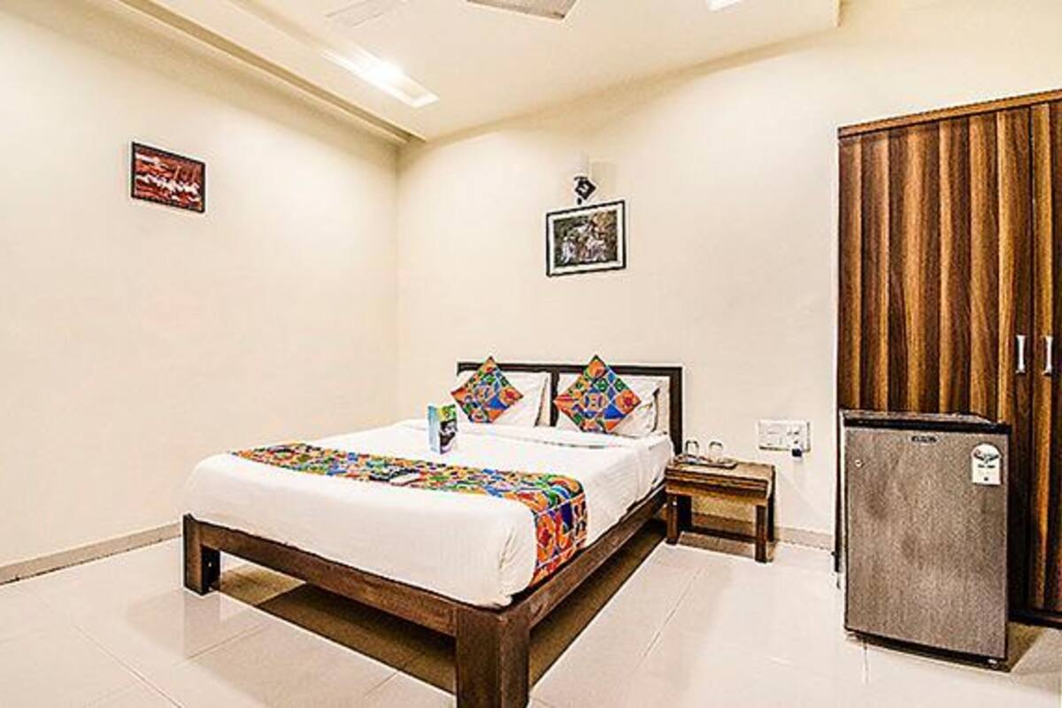 A bedroom with a bed, a nightstand, a refrigerator, and a wardrobe.