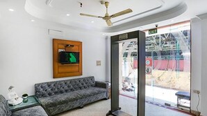 A modern hotel lobby with a grey sofa, a ceiling fan, and an exit sign. - Fabexpress Station Ii (New Delhi)