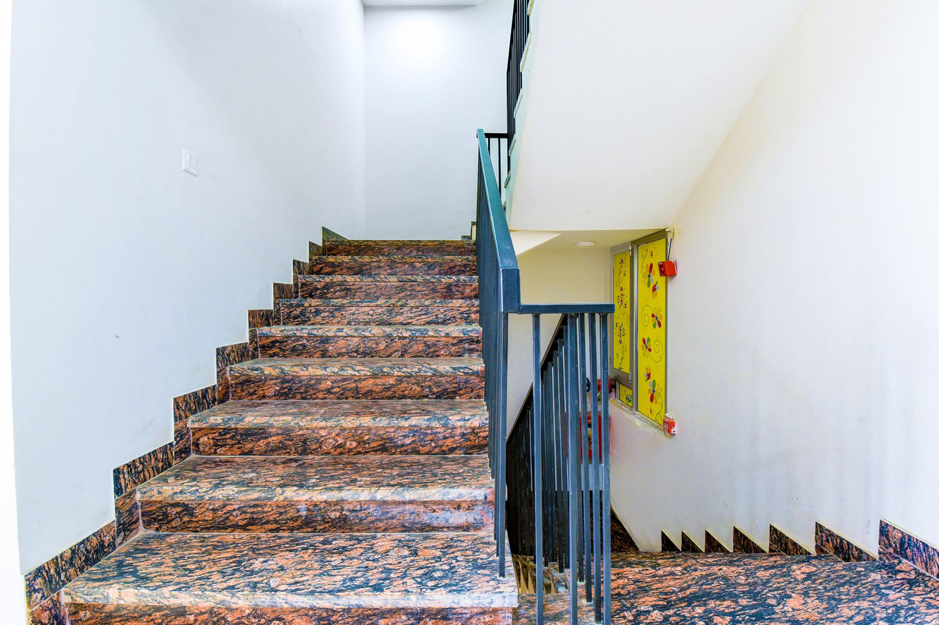 A staircase with a handrail and a yellow door at the top.