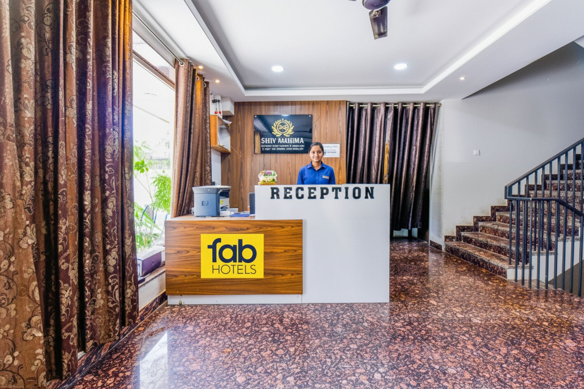 Una recepción con un letrero que dice "fab hotels" y otro letrero encima que dice "SHIV AAAAIMA".
